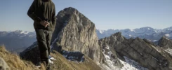 Auto-portrait d’un photographe au col de Balafrasse, debout avec une paire de jumelles à la main, bonnet sur la tête, dans une ambiance de montagne froide.