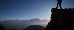 Silhouette d’un photographe sur une crête à contre-jour avec la chaîne du Mont-Blanc en arrière-plan.