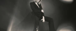 Portrait en noir et blanc d'une femme en tailleur noir assise sur une chaise, attitude de cheffe, superbe bokeh